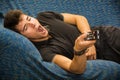 Young bored man sitting on sofa watching Royalty Free Stock Photo