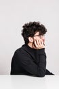 Young bored man in a studio, sitting at the table. Royalty Free Stock Photo