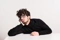 Young bored man in a studio, sitting at the table. Royalty Free Stock Photo