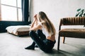 Young bored millennial woman sitting on a floor alone at home. Fatigue or emotionally exhausted concept Royalty Free Stock Photo