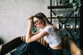 Young bored millennial woman sitting on a sofa alone at home. Fatigue or emotionally exhausted concept Royalty Free Stock Photo