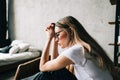 Young bored millennial woman sitting on a sofa alone at home. Fatigue or emotionally exhausted concept Royalty Free Stock Photo