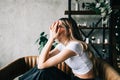 Young bored millennial woman sitting on a sofa alone at home. Fatigue or emotionally exhausted concept Royalty Free Stock Photo