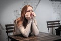 Young bored woman sitting at a table waiting Royalty Free Stock Photo