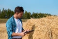 Young botanist man with tablet estimates the hay crop