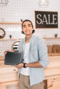 Young boutique owner holding digital tablet with blank screen and smiling at camera