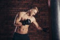 A young boxer in black gloves with a naked torso work out strikes on punching bag. Royalty Free Stock Photo