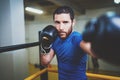 Young boxer doing some training on punching bag on ring. Bearded caucasian boxer training workout exercise in gym Royalty Free Stock Photo