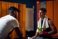 Young boxer in dressing room sitting with coach and talking. Personal trainer encouraging young player