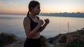 Young boxer girl posing by the sea over huge cliffs at sunset. She wears tights and sports bra Royalty Free Stock Photo