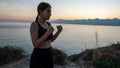 Young boxer girl posing by the sea over huge cliffs at sunset. She wears tights and sports bra Royalty Free Stock Photo