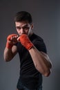 Young boxer with red bandages on hands posing in orthodox stance Royalty Free Stock Photo