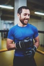 Young boxing man with boxing gloves smiling on ring.Caucasian athlete in black gloves prepairing for kickboxing training