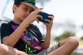 Young boy alone playing with smartphone in the park