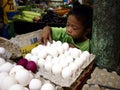 A young boy arranges fresh eggs on a tray at a public market.