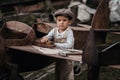 A young boy aviator in a homemade airplane in a natural landscape with a machine tool in his hands repairs a wing. The