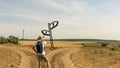 A young boy with a backpack stands at a fork in two roads at the road sign solving the problem of choosing the right path in life