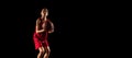 Portrait of young boy, basketball player in motion, training isolated over black background Royalty Free Stock Photo