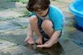 young boy in a bathing suit playing in a puddle of water in the backyard next to a shallow swimming pool Royalty Free Stock Photo