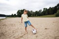 A young boy on the beach runs towards a soccer ball and wants to score a goal