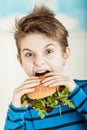 Young boy biting into a salad burger