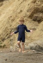 Young boy with blonde hair and navy swimsuit having fun splashing at the beach Royalty Free Stock Photo