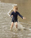 Young boy with blonde hair and navy swimsuit having fun splashing at the beach Royalty Free Stock Photo