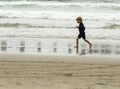 Young boy with blonde hair and navy swimsuit having fun splashing at the beach Royalty Free Stock Photo