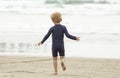 Young boy with blonde hair and navy swimsuit having fun splashing at the beach Royalty Free Stock Photo