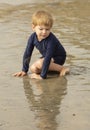 Young boy with blonde hair and navy swimsuit having fun splashing at the beach Royalty Free Stock Photo