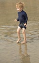 Young boy with blonde hair and navy swimsuit having fun splashing at the beach Royalty Free Stock Photo