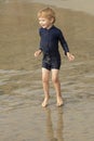 Young boy with blonde hair and navy swimsuit having fun splashing at the beach Royalty Free Stock Photo