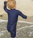 Young boy with blonde hair and navy swimsuit having fun splashing at the beach Royalty Free Stock Photo