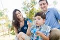 Young Boy Blowing Bubbles with His Parents in the Park. Royalty Free Stock Photo