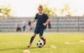 Young boy in blue soccer jersey uniform running after ball on training pitch Royalty Free Stock Photo