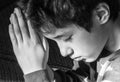 Young boy bowing his head and praying solemnly, black and white