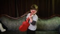 A young boy with a bowl style haircut dances around while strumming a ukulele. He has a big grin and is very happy