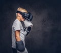 Schoolboy boxer with blonde hair dressed in a white t-shirt wearing visual reality glasses and boxing gloves, workout in Royalty Free Stock Photo