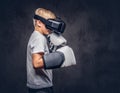 Schoolboy boxer with blonde hair dressed in a white t-shirt wearing visual reality glasses and boxing gloves, workout in Royalty Free Stock Photo