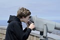 A young boy on Brasstown Bald looking at the view with a telescope.