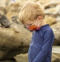 Young boy in a bright face mask playing in tidepools Royalty Free Stock Photo