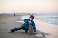 Young boy builds sand castle at the winter beach. Cute 11 years old boy at seaside, evening time. Royalty Free Stock Photo