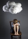 Young boy child sitting on chair with cloud above his head