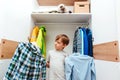 Young boy chooses clothes in the wardrobe closet at home. Cute boy taking school shirt to wear