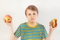 Young boy chooses between fastfood and fresh apple on white background Royalty Free Stock Photo