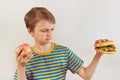 Young boy chooses between fastfood and healthy diet on white background Royalty Free Stock Photo