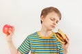 Young boy chooses between hamburger and apple on white background Royalty Free Stock Photo