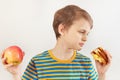 Young boy chooses between sandwich and fruit on white background Royalty Free Stock Photo