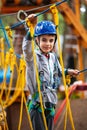 Young boy climbing pass obstacles in rope. Child in forest adventure park