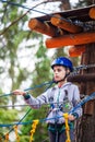 Young boy climbing pass obstacles in rope. Child in forest adventure park